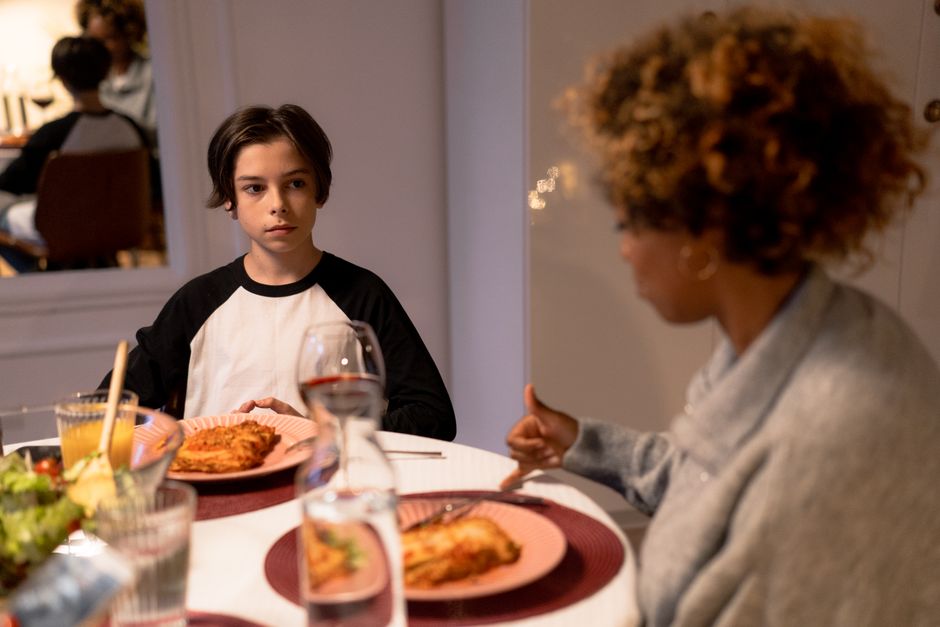 Parent and teenager having a conversation at a kitchen table